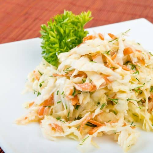 Low fat vegetable salad coleslaw (cabbage, carrot, dill,  mayonnaise) on plate at restaurant table