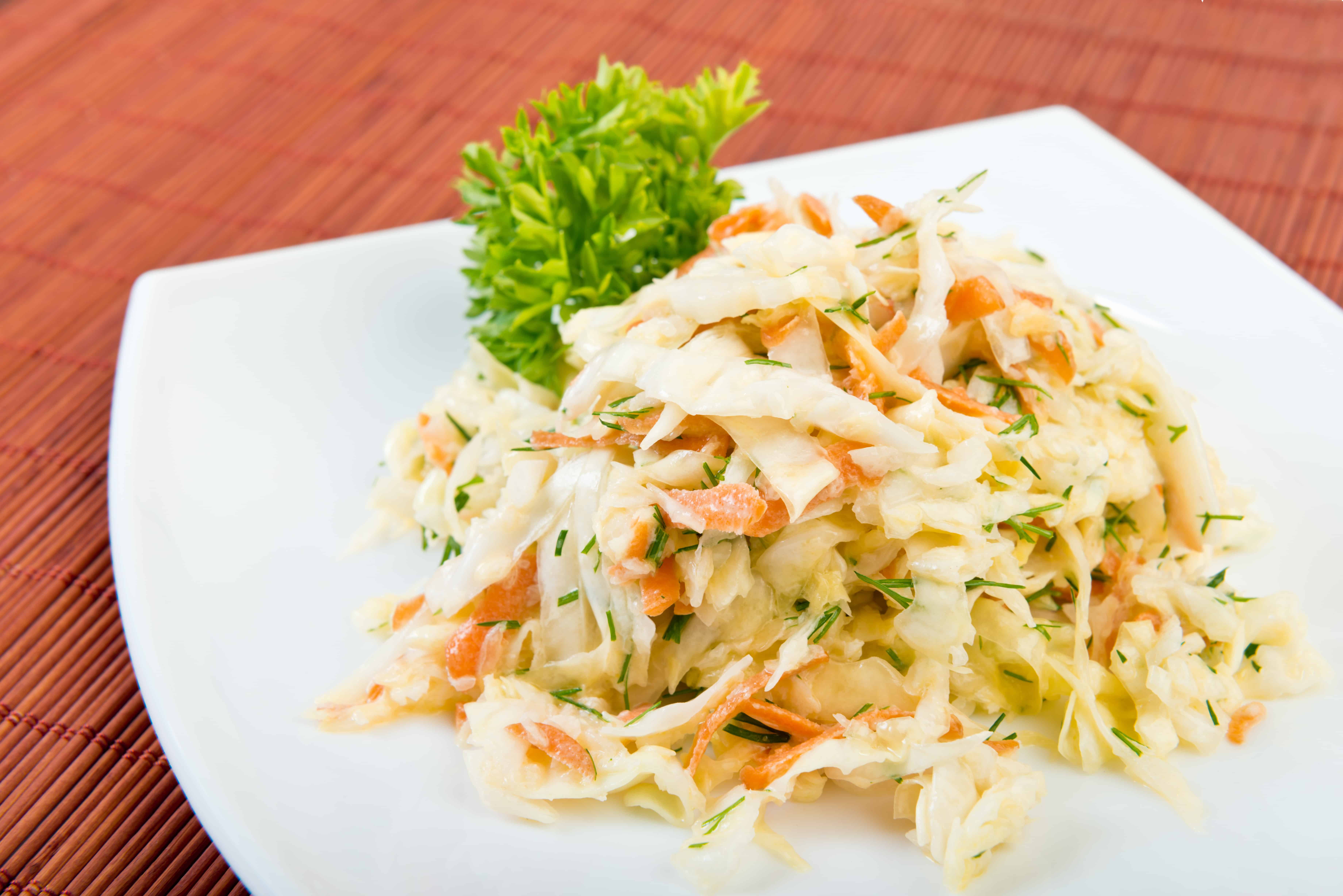 Low fat vegetable salad coleslaw (cabbage, carrot, dill,  mayonnaise) on plate at restaurant table