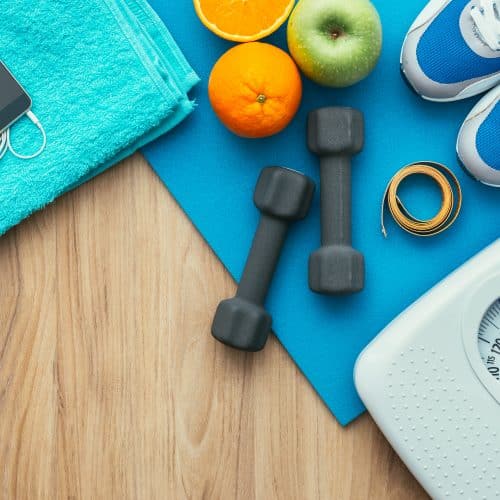 Sports and workout equipment on a wooden floor with healthy snacks, weight loss and physical activity concept