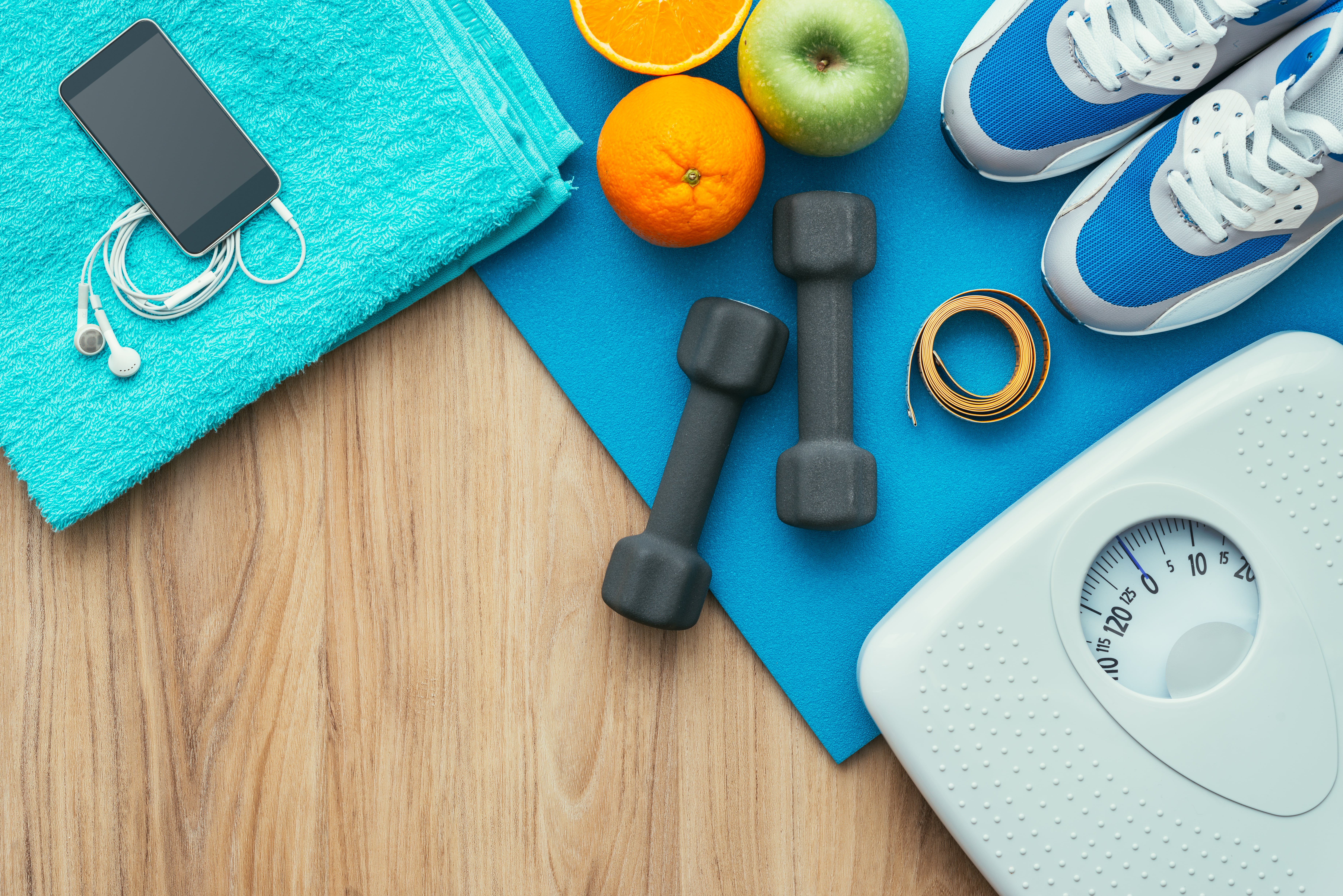 Sports and workout equipment on a wooden floor with healthy snacks, weight loss and physical activity concept