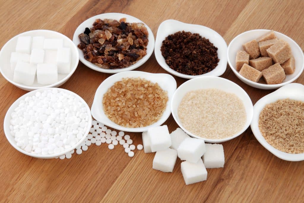 Sugar selection in white porcelain dishes over oak background.