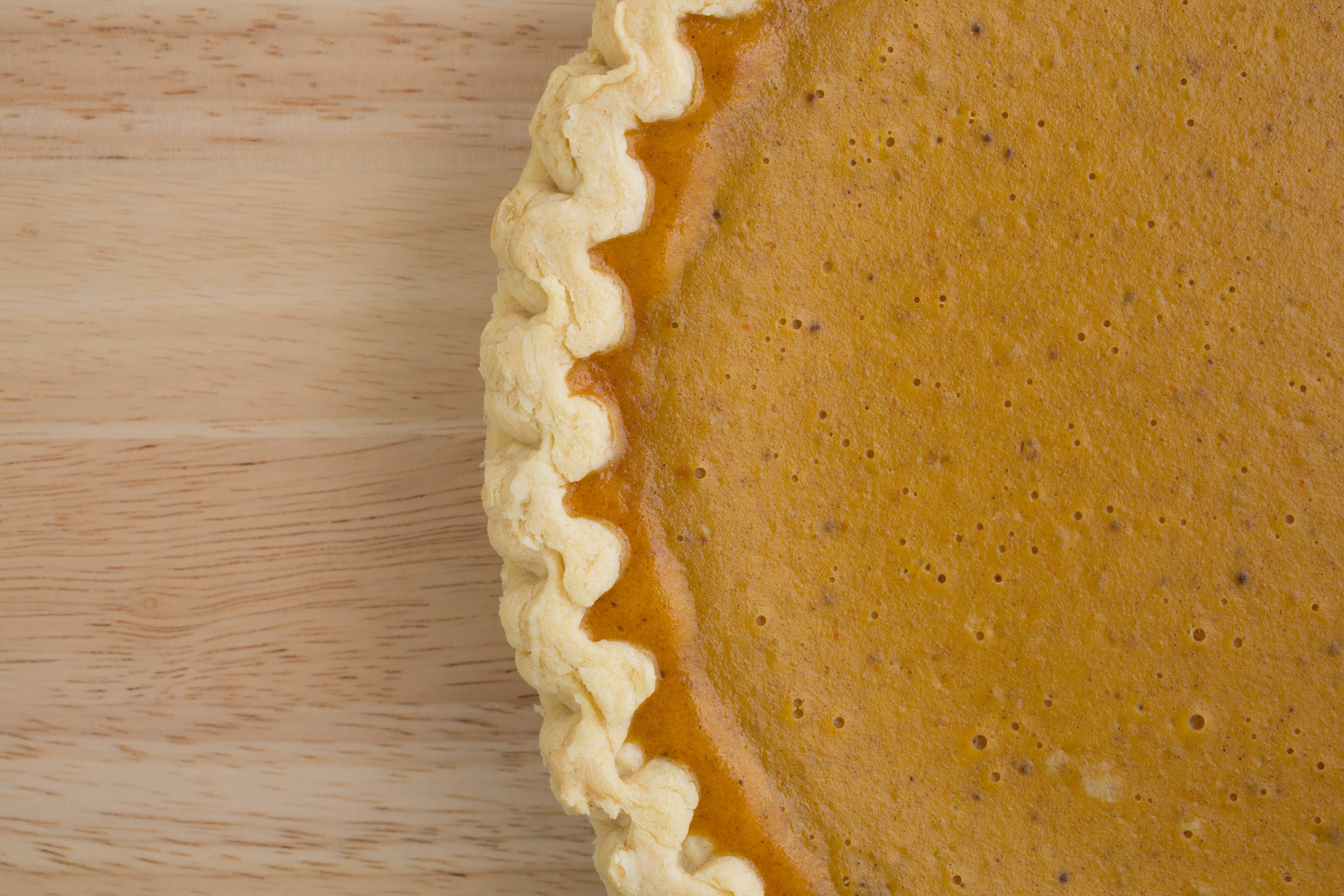 A very close view of a fresh pumpkin pie on a wood table top.