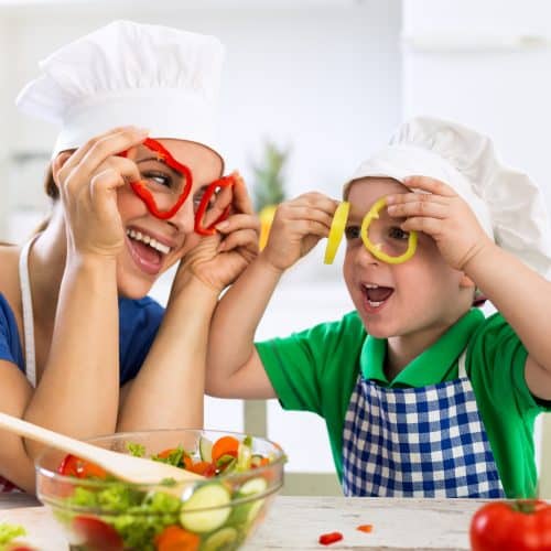 Happy family playing with vegetables in kitchen at home