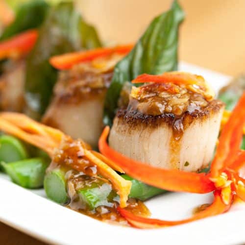 Spicy thai scallops on a bed of asparagus spears.