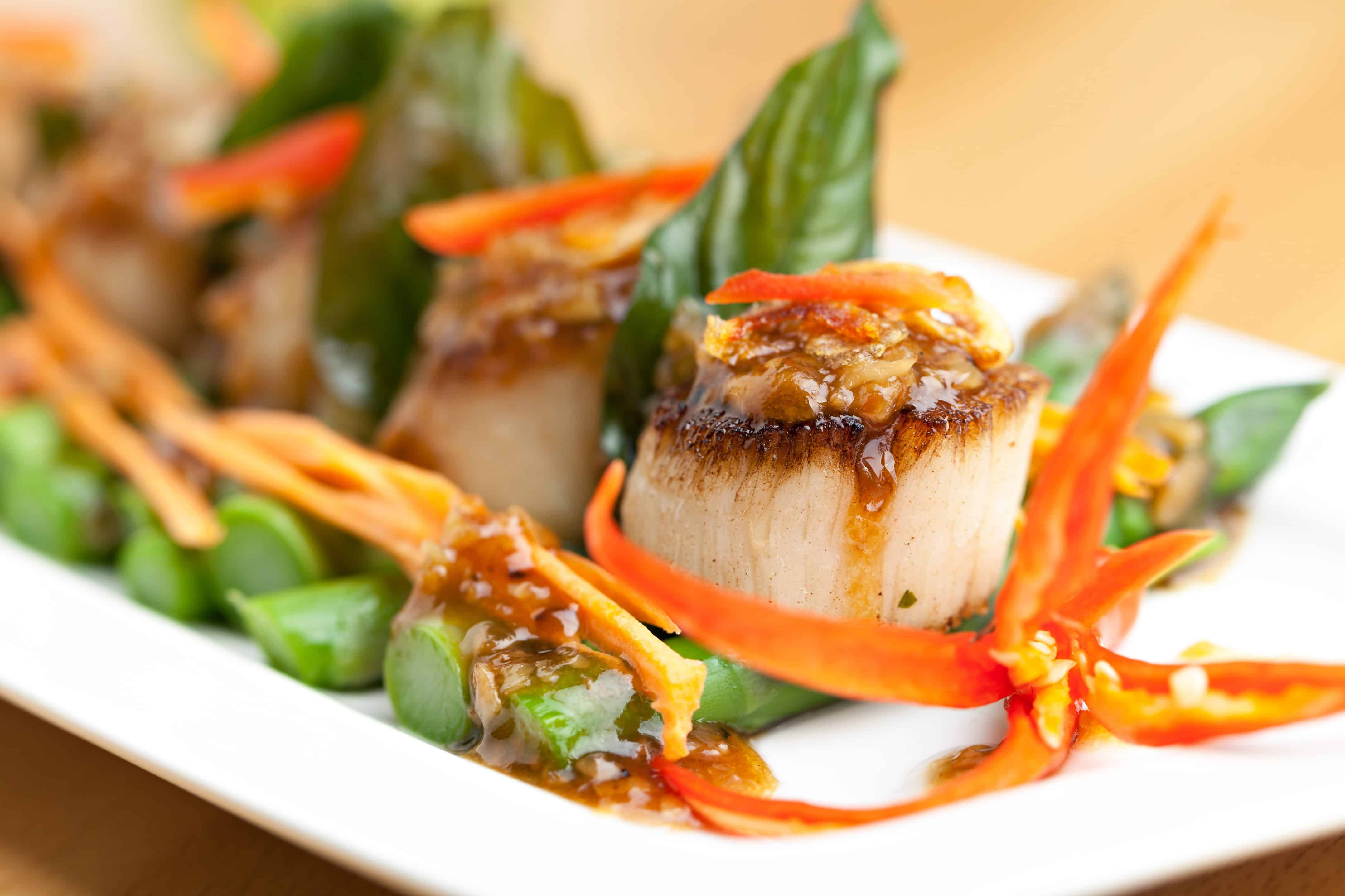 Spicy thai scallops on a bed of asparagus spears.
