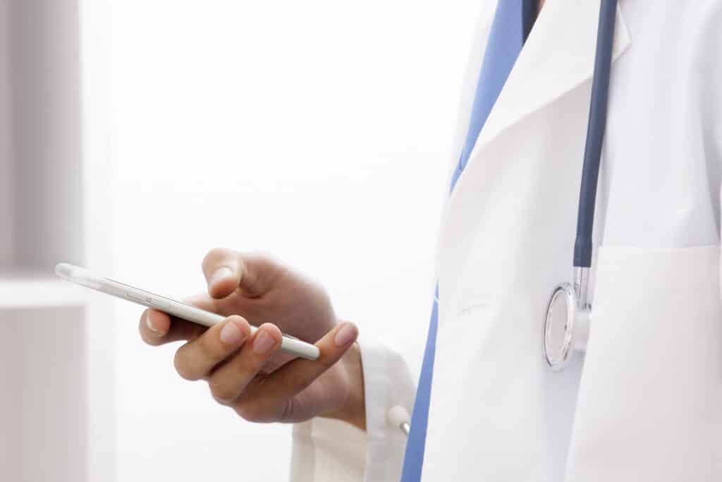 doctor with mobile phone in hands in office